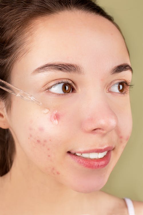 Woman applying LUMÉ microcurrent serum to face
